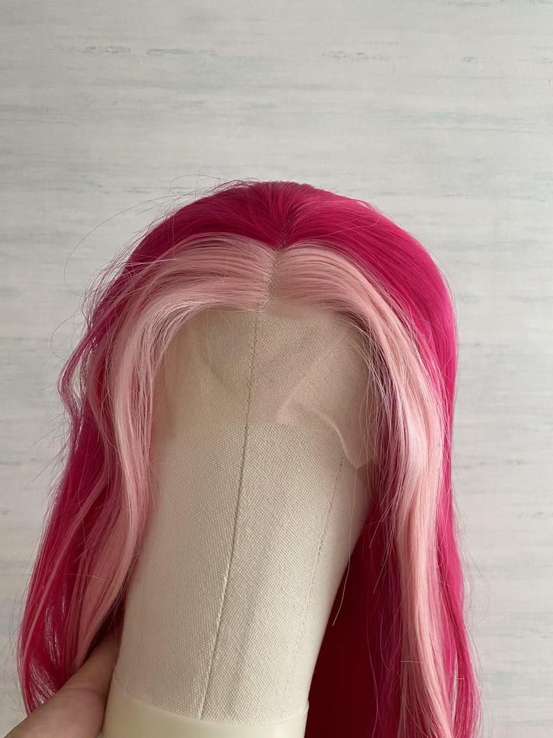 Pode incluir: Uma peruca rosa vibrante e rosa claro com cabelo longo e ondulado. A peruca apresenta uma coroa rosa escuro e uma se&ccedil;&atilde;o frontal rosa claro. A peruca &eacute; estilizada em uma cabe&ccedil;a de manequim, mostrando a cor e o estilo.