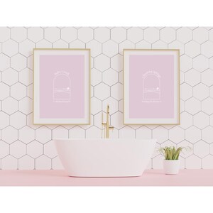 Puede incluir: Dos impresiones enmarcadas con fondos rosas y texto blanco. El texto de la impresión de la izquierda dice "Rise & Grind" y el texto de la impresión de la derecha dice "The good vibes" con una pequeña ilustración de una ventana con una escena de paisaje debajo de cada una.