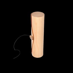 May include: A cylindrical wooden box with a natural finish and a black cord with a button closure.