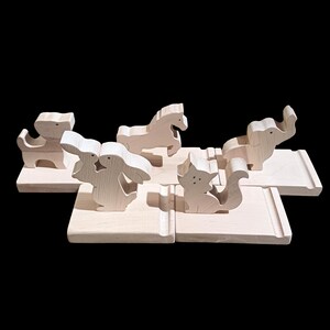 May include: Wooden animal figurines on a set of wooden bases. The animals include a horse, a cat, a rabbit, a dog, and an elephant. The bases are all the same size and shape, and they are made of natural wood.