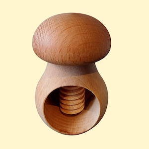May include: A wooden nutcracker shaped like a mushroom. The top of the nutcracker is a rounded mushroom cap, and the bottom is a hollowed-out base with a screw mechanism for cracking nuts.