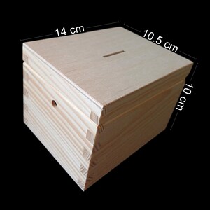 May include: A light-colored wooden box with a rectangular slot on the top lid and a small circular hole on the front panel. The box features visible finger joints at the corners and measures 14 cm in length, 10.5 cm in width, and 10 cm in height.