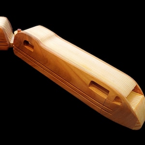 May include: A wooden toy train with a brown and natural wood finish. The train is made of two pieces, a locomotive and a car. The locomotive has a rounded front and a rectangular body. The car has a rectangular body. The train is a simple design with no wheels or other details.