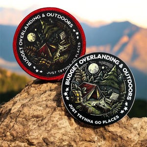 Può includere: Due toppe rotonde nere e bianche con cuciture rosse. Le toppe mostrano una scena di campeggio con una tenda, un falò e stelle. Il testo sulle toppe recita "Budget Overlanding & Outdoors" e "Just Trynna Go Places".