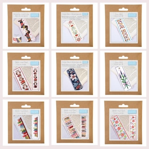 May include: Nine cross-stitch bookmark kits in brown packaging. Designs include floral, owl, and book themes. Each kit contains a bookmark with a cross-stitch pattern, needle, and thread. The text on the packaging reads "Stitch Your Own".