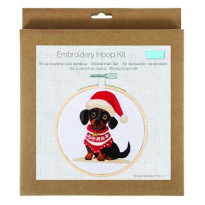 May include: Embroidery hoop kit with a dachshund wearing a Santa hat and sweater. The embroidery is set in a wooden hoop, with a finished diameter of 10cm. The kit is packaged in a brown cardboard box.