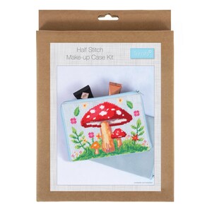 May include: A craft kit for a half-stitch make-up case. The case features a cross-stitch design of a red mushroom with white spots, green grass, and flowers. The kit is packaged in a brown cardboard box.