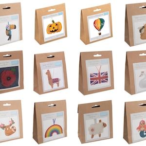 May include: A selection of craft kits in brown paper bags, each with a unique design. Designs include a toucan, pumpkin, hot air balloon, bee and hive, poppy, llama, Union Jack, swan, sloth, rainbow, sheep, and mermaid. Each kit has the text "Make Your Own Decoration Kit."