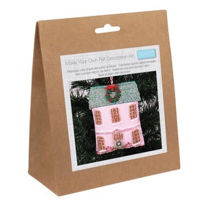 May include: A brown paper bag containing a felt decoration kit. The kit features a pink felt house ornament with a green roof and a small wreath. The text on the package reads "Make Your Own Felt Decoration Kit."