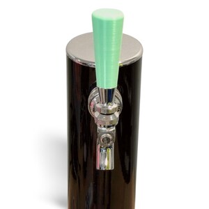 May include: A black and silver beer tap with a mint green handle. The tap has a shiny, metallic finish and is designed for dispensing beverages. The tap is mounted on a black cylinder with a silver top.