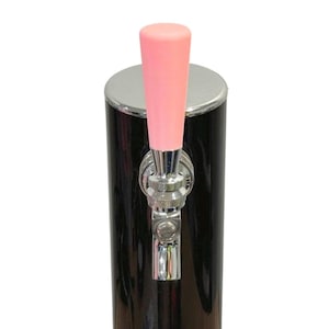 May include: A black beer tap with a pink handle and a chrome faucet. The tap is cylindrical with a shiny finish. The handle is a solid, light pink color. The faucet is made of chrome.