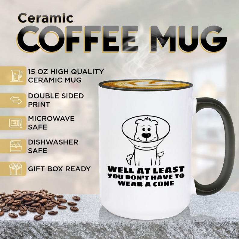 May include: A white 15 oz ceramic coffee mug with a black handle and rim. The mug features a black line drawing of a dog wearing a cone collar with the text: WELL AT LEAST YOU DON'T HAVE TO WEAR A CONE. The mug is microwave and dishwasher safe.