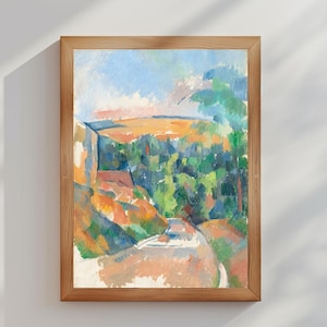 May include: A framed landscape painting with a wooden frame. The artwork depicts a colorful scene with green trees, orange and yellow fields, and a blue sky. The painting is mounted on a white wall with shadows.