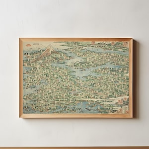 以下が含まれることがあります： 江戸の地図が描かれた、木製の額縁に入ったヴィンテージプリント。富士山が背景に描かれている。地図は青、緑、茶色の色合いで、都市のレイアウトが複雑に描かれている。