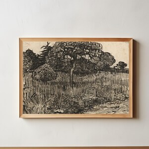 May include: A framed black and white landscape print. The artwork depicts a field with tall grass, trees, and a detailed sky. The print is in a light brown wooden frame, and the artwork is on a cream-colored background.