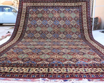 May include: A large, intricately patterned rug with a deep red, blue, and green colour scheme. The rug has a central medallion design and a border with floral motifs.