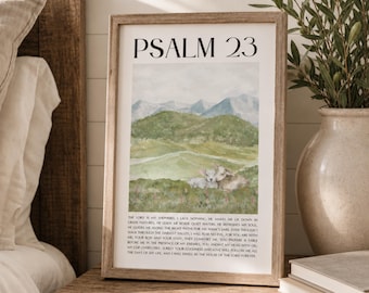 May include: A framed wall art print featuring the text Psalm 23 in black font at the top, a watercolor illustration of green hills, mountains, and two sheep in the center, and the full text of the psalm printed in small black letters at the bottom.