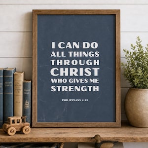 Puede incluir: Una lámina de arte mural enmarcada con fondo azul oscuro y texto blanco que dice: I CAN DO ALL THINGS THROUGH CHRIST WHO GIVES ME STRENGTH PHILIPPIANS 4:13. El marco es de madera marrón y presenta un diseño rectangular sencillo.