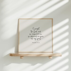 Pode incluir: Uma impressão emoldurada com fundo branco e texto preto. O texto diz "Busquei o Senhor, e ele me respondeu, ele me livrou de todos os meus medos. Salmo 34:4".