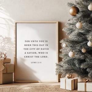 May include: A framed print with a white background and black text. The text reads "For unto you is born this day in the city of David a Savior, who is Christ the Lord. Luke 2:11".