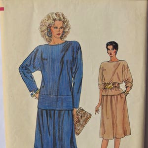 May include: A vintage sewing pattern for a dress with two different styles. The pattern is for sizes 6-8-10 and is called "Very Easy Vogue" with the number 8732 printed on the top. The dress on the left is blue and white striped and the dress on the right is a solid beige.