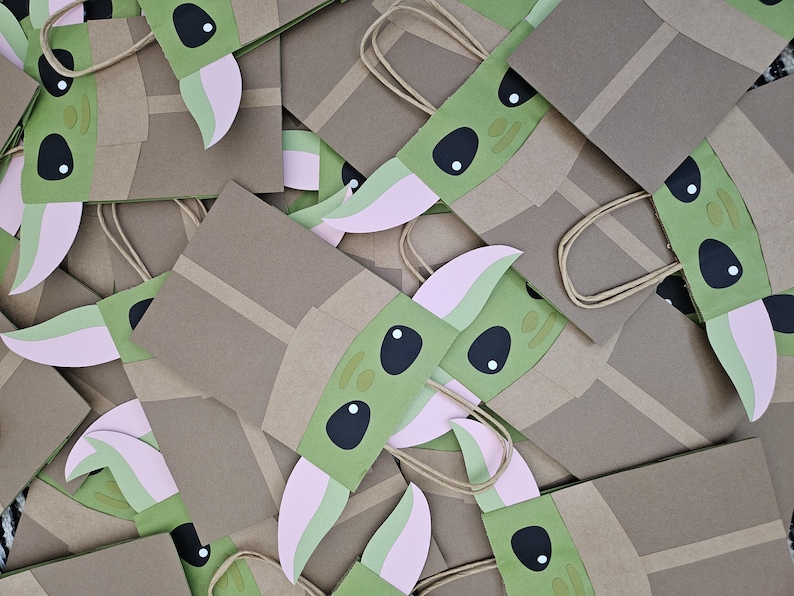 Może przedstawiać: Kolekcja brązowych papierowych torebek na prezenty, każda ozdobiona zielonym, r&oacute;żowym i czarnym wzorem postaci. Torby mają beżowe uchwyty i są ułożone w zbliżeniu, zachodzącym na siebie wzorze.