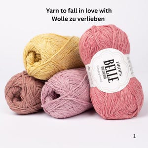 May include: A collection of colorful yarn balls in shades of pink, yellow, and mauve. One ball has a label that reads "BELLE UNI COLOUR Everyday Luxury DROPS". The text "Yarn to fall in love with Wolle zu verlieben" is at the top.