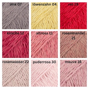 May include: Nine skeins of yarn in various colors, including gray, yellow, red, and shades of pink. Each skein is labeled with a color name and number. The image showcases a range of hues suitable for knitting or crochet projects.