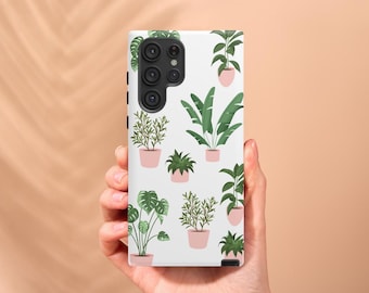 Puede incluir: Una funda de teléfono blanca con un patrón de plantas en macetas en varios tonos de verde. La funda tiene una lente de cámara negra con tres lentes.