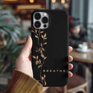 May include: Black phone case with a gold floral design and the word "BREATHE" printed on the bottom.