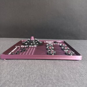 May include: A purple plastic panel with multiple black knobs and a white dial. The panel has a grid of small holes and the text "Sequill Sleep" printed on it.