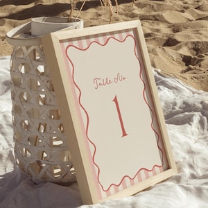 May include: A pink and white striped table number sign with a white background and red text that says "Table No." and the number "1".