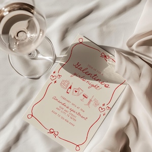 A Galentine Girls Night Invitation card. The design features hand drawn illustrations, including a heart-shaped cake, wine bottle, polaroid pictures, ribbed wine glass, taper candles, cupid, hearts and bows. The font looks handwritten.