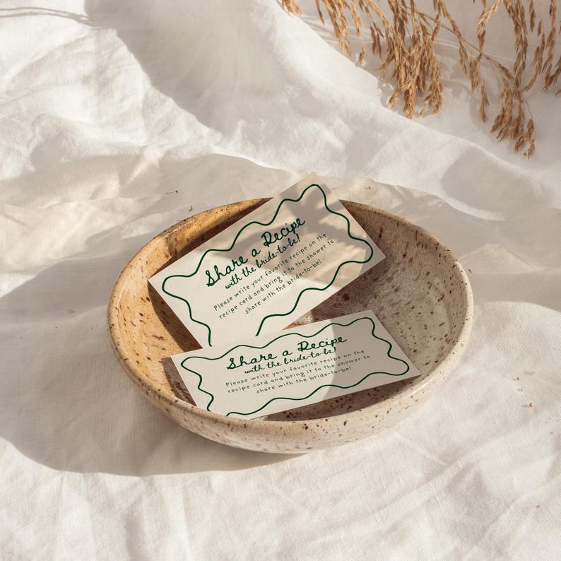 Pu&ograve; includere: Due schede di ricette bianche con testo verde che dice "Condividi una ricetta con la sposa!" Per favore, scrivi la tua ricetta preferita sulla scheda di ricetta e portala alla doccia per condividerla con la sposa!"