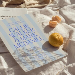 May include: A blue and white striped wedding invitation with the text "Please join us for the wedding of Callie Walker & Mark McDaniel" in blue text. The invitation details the wedding date, time, and location: Saturday, 19th July 2025, two o'clock in the afternoon, Malibu Beach, 1234 Any Street, Malibu, CA.