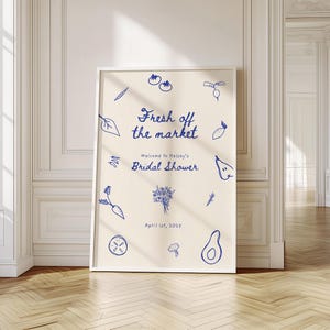 May include: A white poster with blue text and illustrations of vegetables and fruits. The text reads "Fresh off the market" and "Welcome to Kelsey's Bridal Shower" with the date "April 1st, 2025".