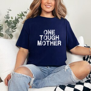 May include: A navy blue t-shirt with the text "ONE TOUGH MOTHER" in white distressed lettering.