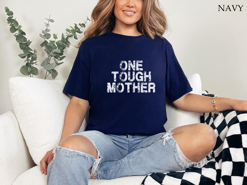 May include: A navy blue t-shirt with the text "ONE TOUGH MOTHER" in white distressed lettering.