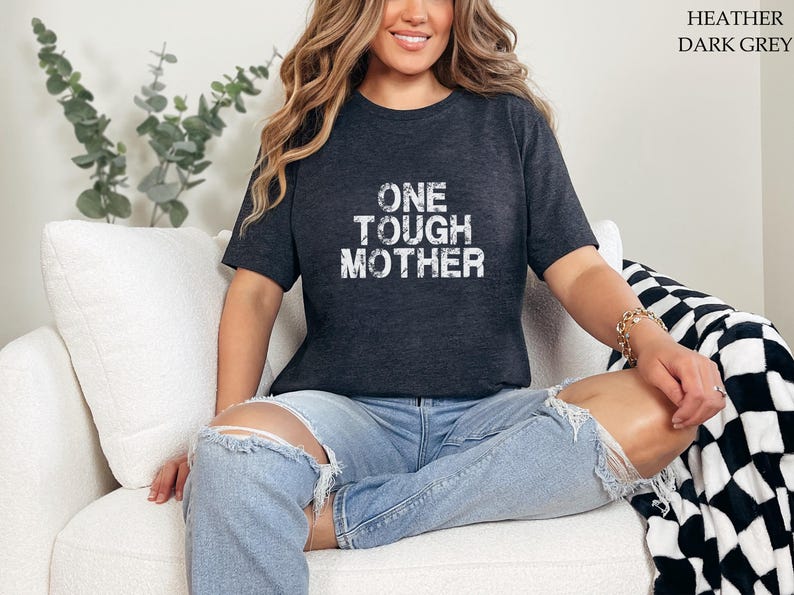 May include: A heather dark grey t-shirt with the text "ONE TOUGH MOTHER" printed in white on the front.