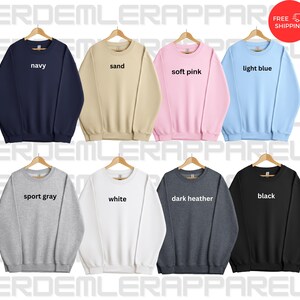 K&ouml;nnte beinhalten: Zehn Crewneck-Sweatshirts, die auf Kleiderb&uuml;geln pr&auml;sentiert werden, jeweils in einer anderen Farbe: marineblau, sandfarben, zartrosa, hellblau, sportgrau, wei&szlig;, dunkelgrau meliert, schwarz. Der Farbname ist auf jedem Sweatshirt aufgedruckt.
