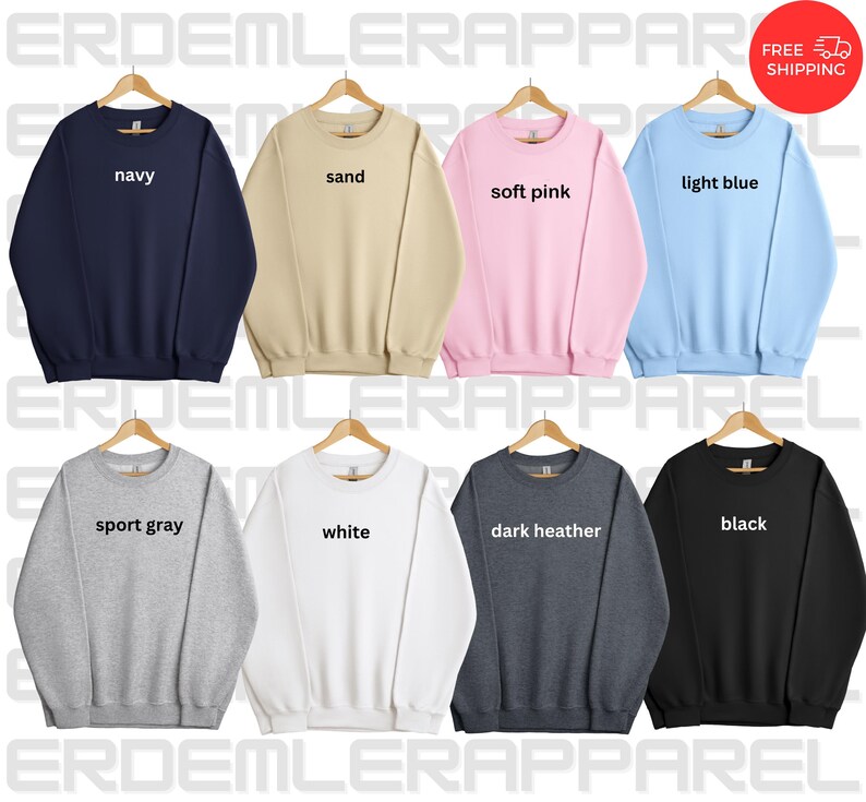 K&ouml;nnte beinhalten: Zehn Crewneck-Sweatshirts, die auf Kleiderb&uuml;geln pr&auml;sentiert werden, jeweils in einer anderen Farbe: marineblau, sandfarben, zartrosa, hellblau, sportgrau, wei&szlig;, dunkelgrau meliert, schwarz. Der Farbname ist auf jedem Sweatshirt aufgedruckt.