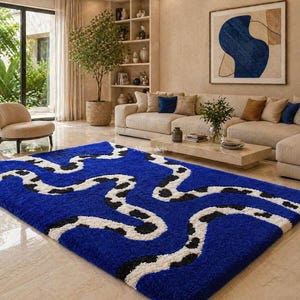 May include: A rectangular rug with a deep blue base, featuring a flowing design in white and black. The rug is placed in a living room setting. The rug's design creates a bold contrast.
