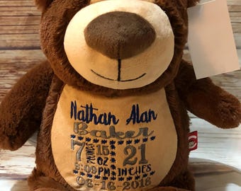 Könnte beinhalten: Ein brauner Plüschteddybär mit beigem Bauch, bestickt mit dem Text: Nathan Alan Baker, 7 pounds 15 oz, 21 inches, 9:09 PM und 06-16-2018. Der Bär hat eine beige Schnauze, schwarze Augen, eine dunkelbraune Nase und ein leeres weißes Etikett.