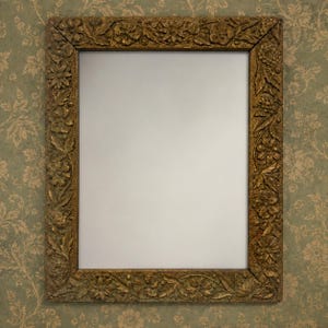 May include: A rectangular mirror featuring a thick, ornate frame with a dark gold finish. The frame is decorated with detailed, raised carvings of various flowers and leaves that extend across all four sides of the rectangular border.