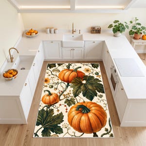 May include: A rectangular area rug featuring a botanical print of large orange pumpkins, dark green leaves, and winding vines on a cream-colored background. The design includes small clusters of berries and delicate floral elements throughout the pattern.