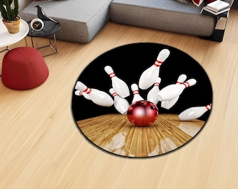 Könnte beinhalten: Ein runder Teppich mit schwarzem Hintergrund und einer Bowlingkugel und Kegeln in Strike-Position. Die Bowlingkugel ist rot und die Kegel sind weiß mit roten Streifen.