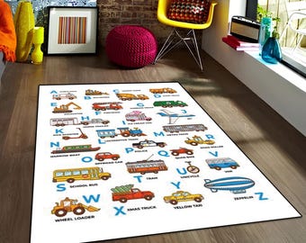 Könnte beinhalten: Ein rechteckiger weißer Teppich mit einem bunten Alphabet-Design, bei dem jeder Buchstabe von A bis Z mit einer entsprechenden Fahrzeugillustration und deren Namen versehen ist, darunter Krankenwagen, Planierraupe und Schulbus.