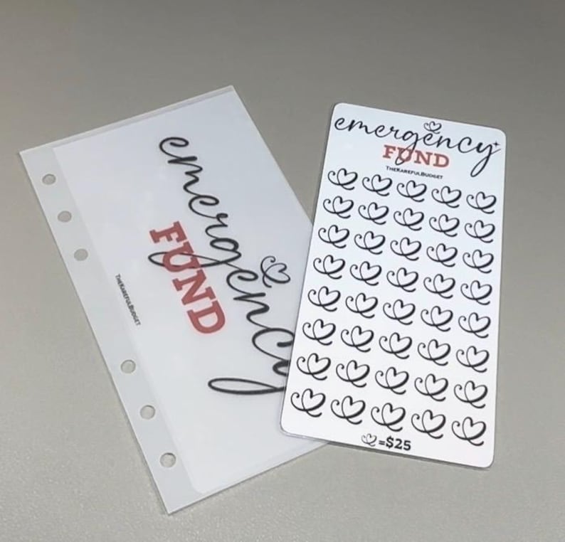 May include: A translucent plastic binder insert with five holes and a white card featuring the text emergency FUND and a grid of 35 black heart icons. The card includes the text THEKAREFULBUDGET and the notation heart equals $25 at the bottom.