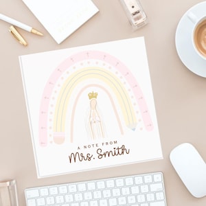 Puede incluir: Bloc de notas cuadrado con un diseño de arcoíris en colores pastel, una figura coronada y el texto "A Note From Mrs. Smith". La imagen incluye artículos de oficina como un teclado y una taza de café.