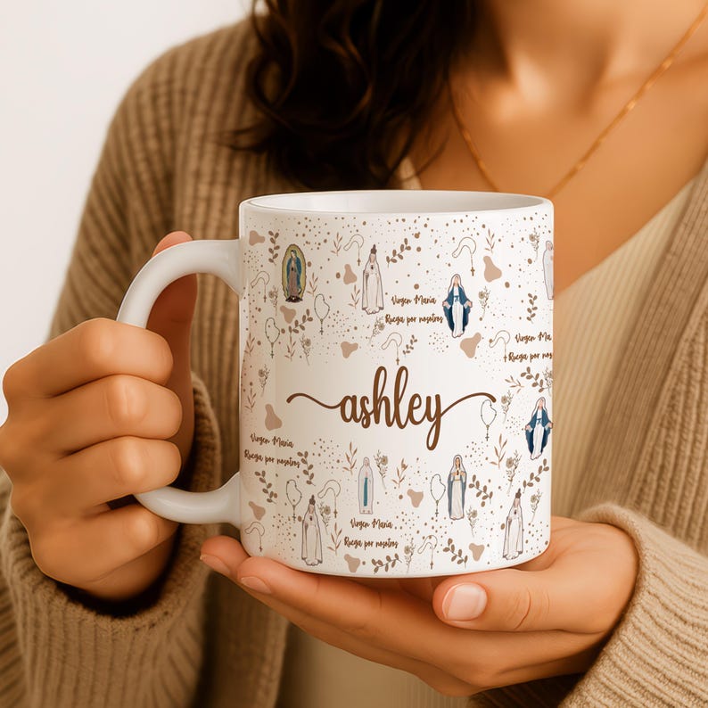 Peut inclure: Une tasse en c&eacute;ramique blanche avec une anse noire et le texte "But First, Coffee" en noir gras. La tasse est pos&eacute;e sur une surface en bois. La tasse semble contenir environ 355 ml.